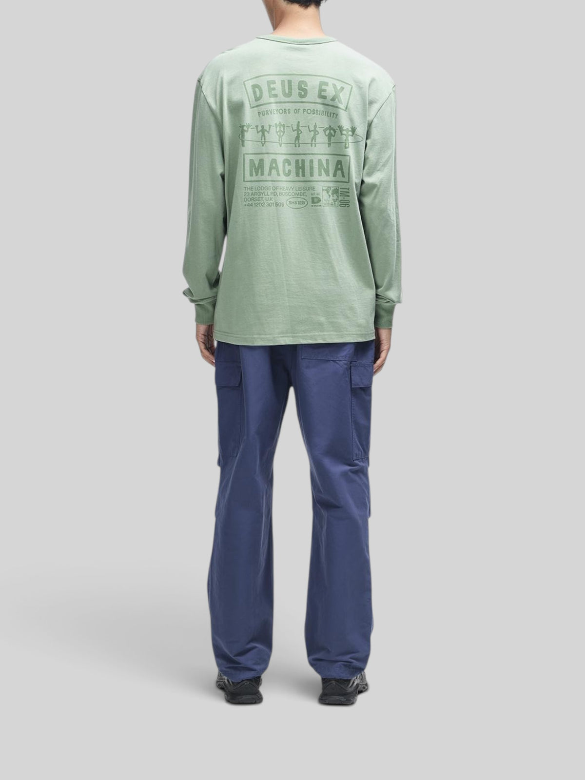 Baffle Haus Kumbaya long sleeve tee in loden frost green with graphic print on back, worn with blue cargo pants