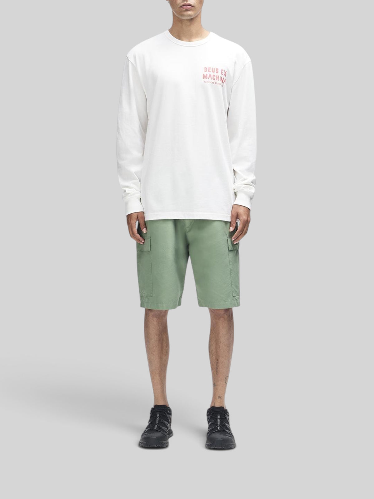Baffle Haus Kumbaya long sleeve tee in vintage white with chest graphic, worn by a model with green cargo shorts.