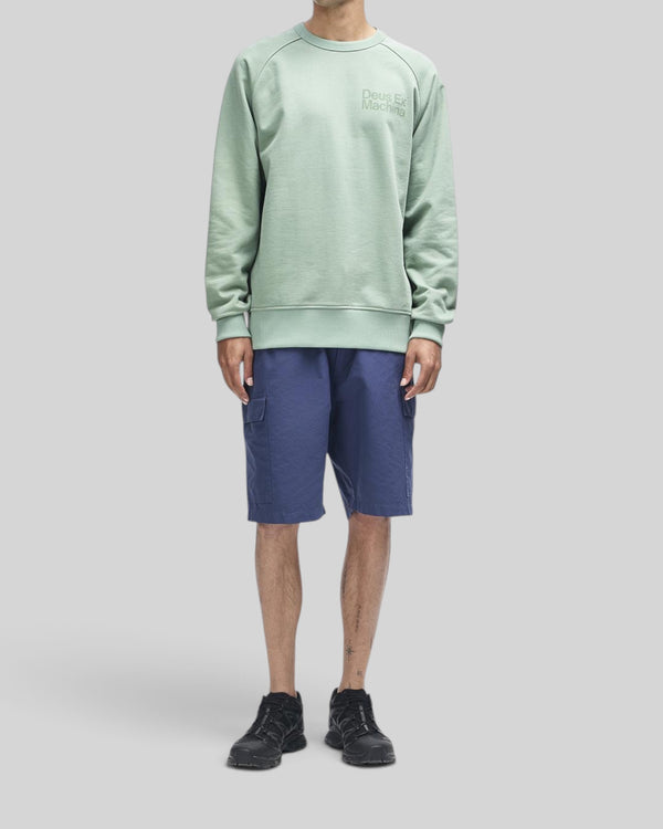 Baffle Haus Plenty Good Crew in loden frost green with chest print and nylon sleeve panels on a model