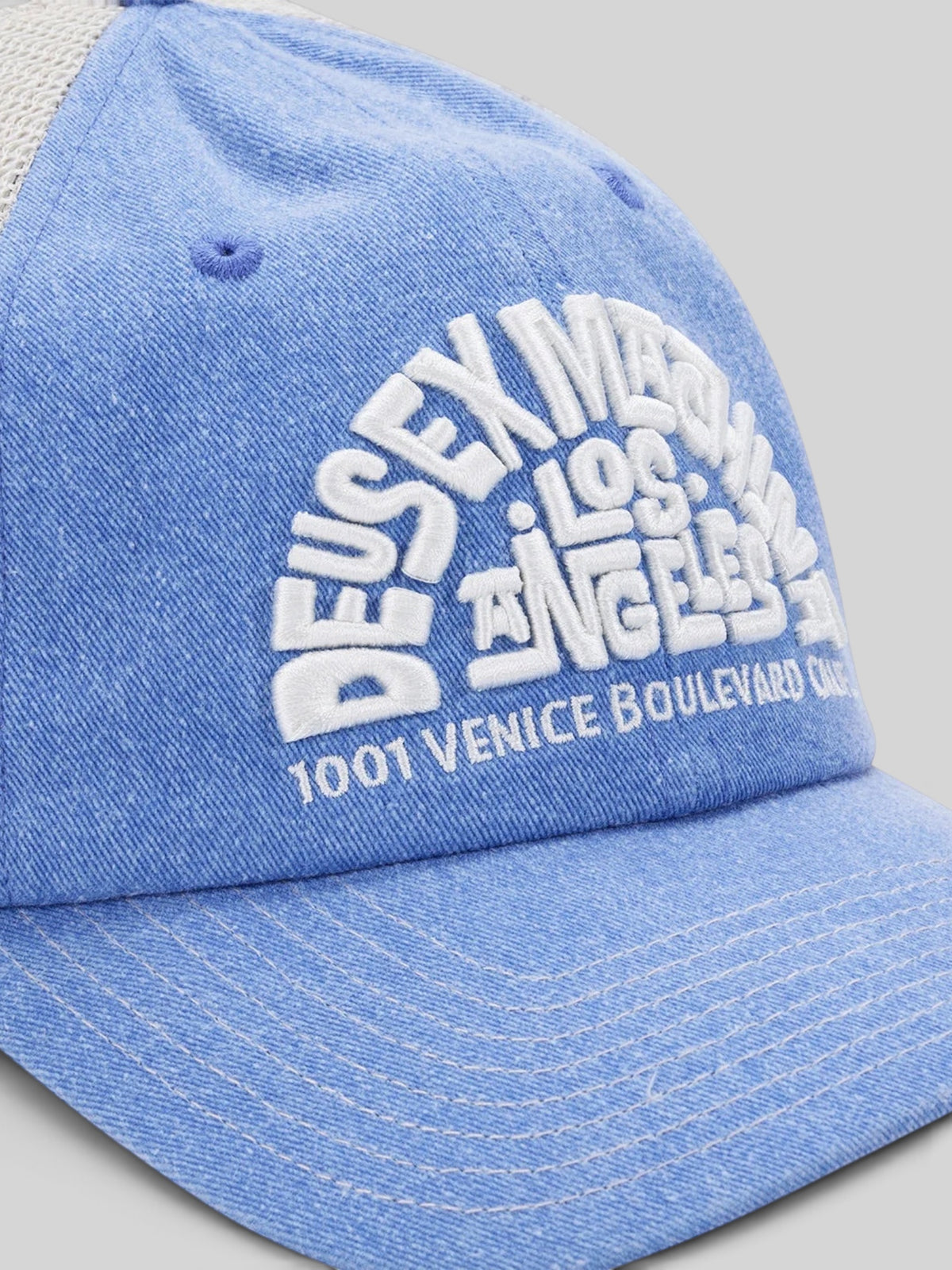 Baffle Haus Los Angeles Address trucker hat in Bonnie Blue with white embroidered text and contrast stitching.