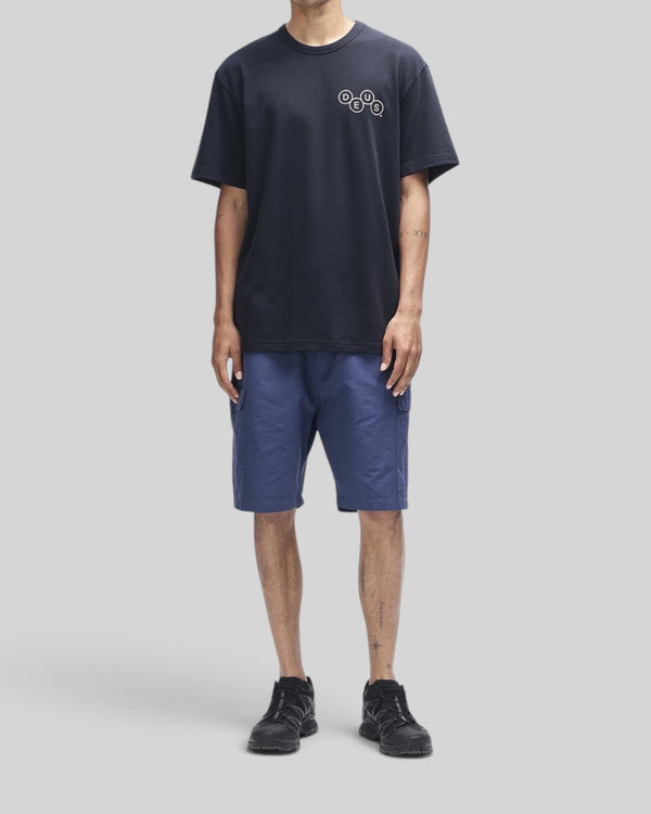 Baffle Haus Mechanism black short sleeve tee in organic cotton with chest graphic, worn with blue cargo shorts.