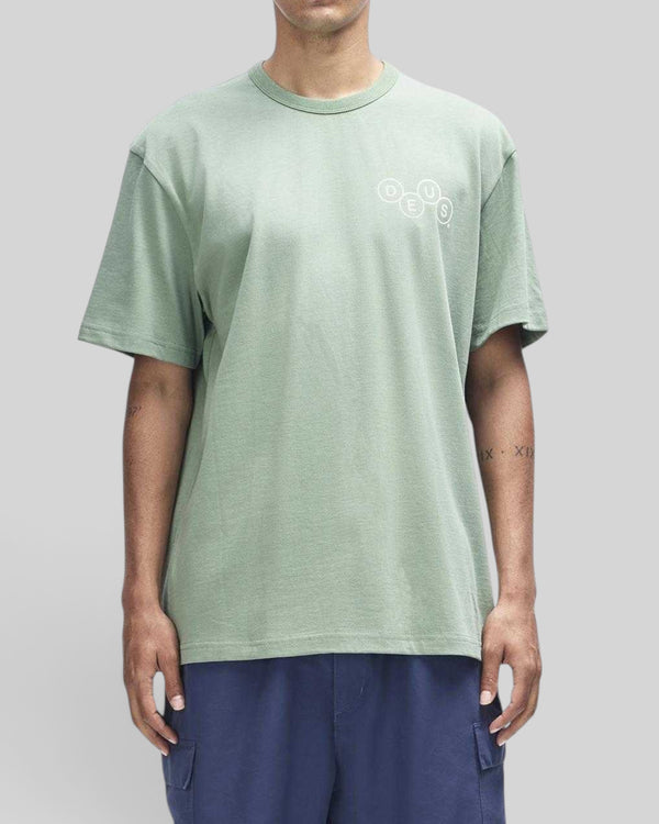 Baffle Haus Mechanism Tee in loden frost green organic cotton with a small circular chest graphic print.