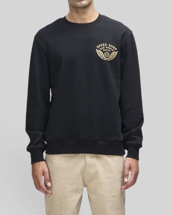 Baffle Haus Munificence crew neck fleece in black with gold Deus Speed Shop chest graphic on a male model