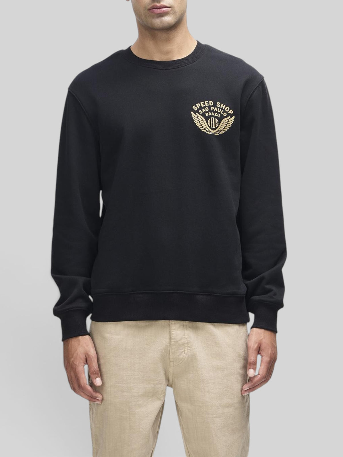 Baffle Haus Munificence crew neck fleece in black with gold Deus Speed Shop chest graphic on a male model