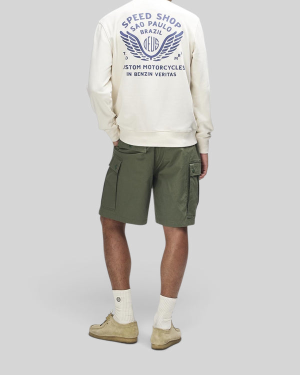 Baffle Haus Munificence crew fleece in dirty white with blue graphic print on back, worn with olive cargo shorts.