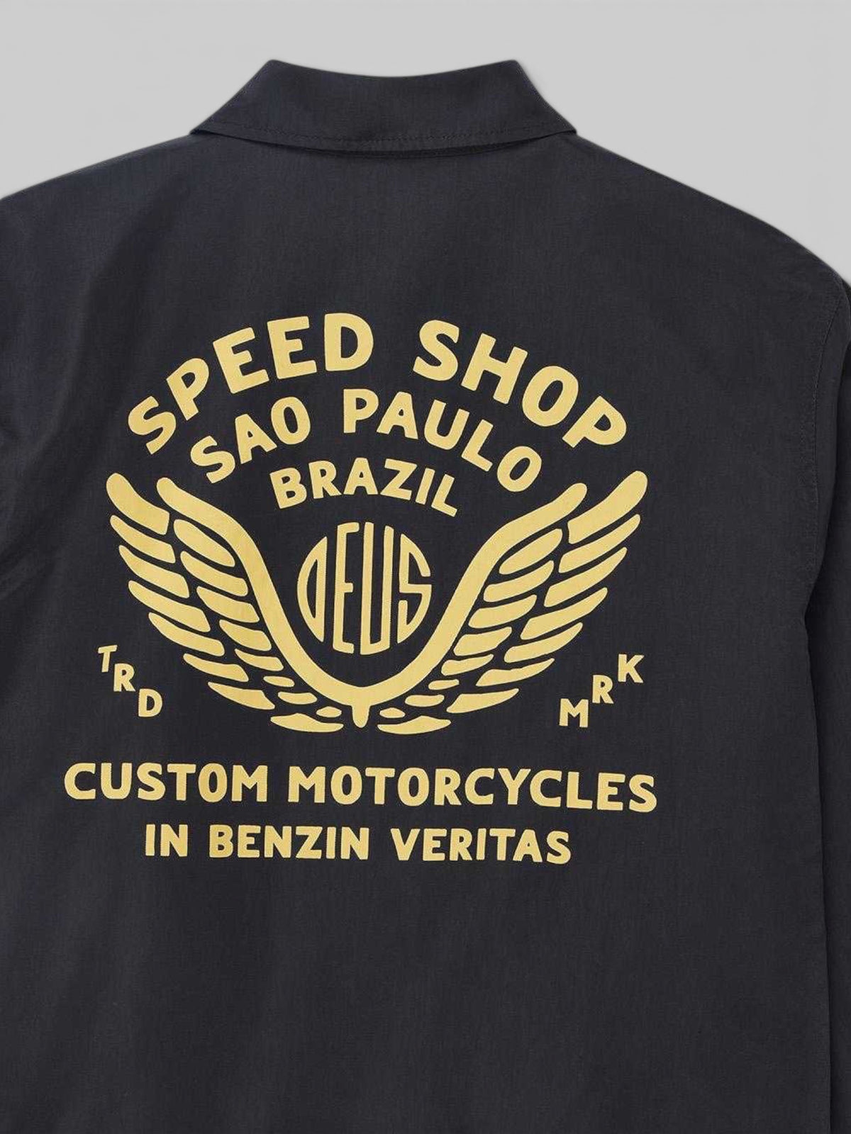 Baffle Haus Munificence black nylon coach jacket featuring gold Deus Speed Shop Sao Paulo graphic print on the back