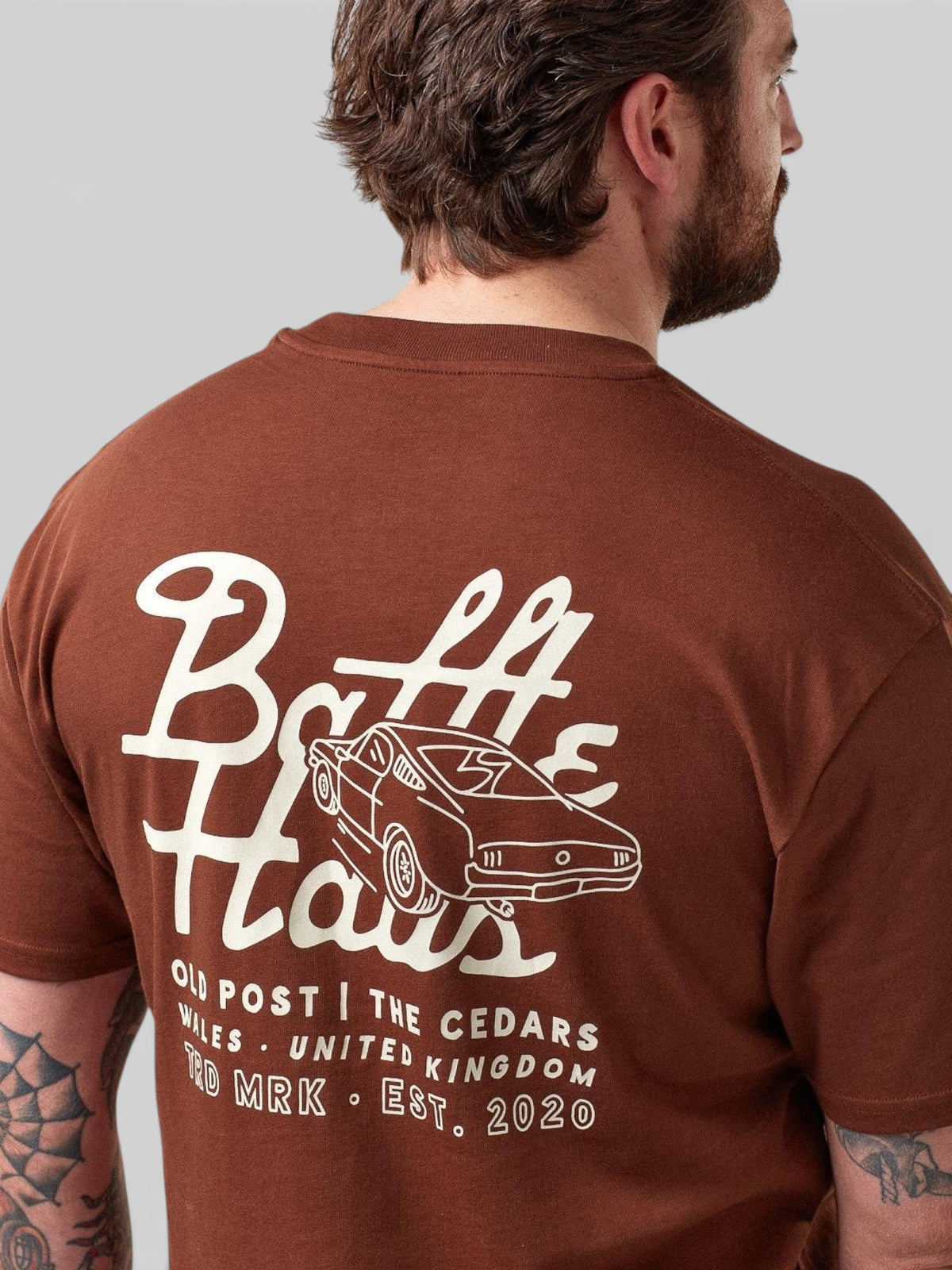 Baffle Haus cocoa brown cotton t-shirt with white mustang car graphic on the back, worn by a man.