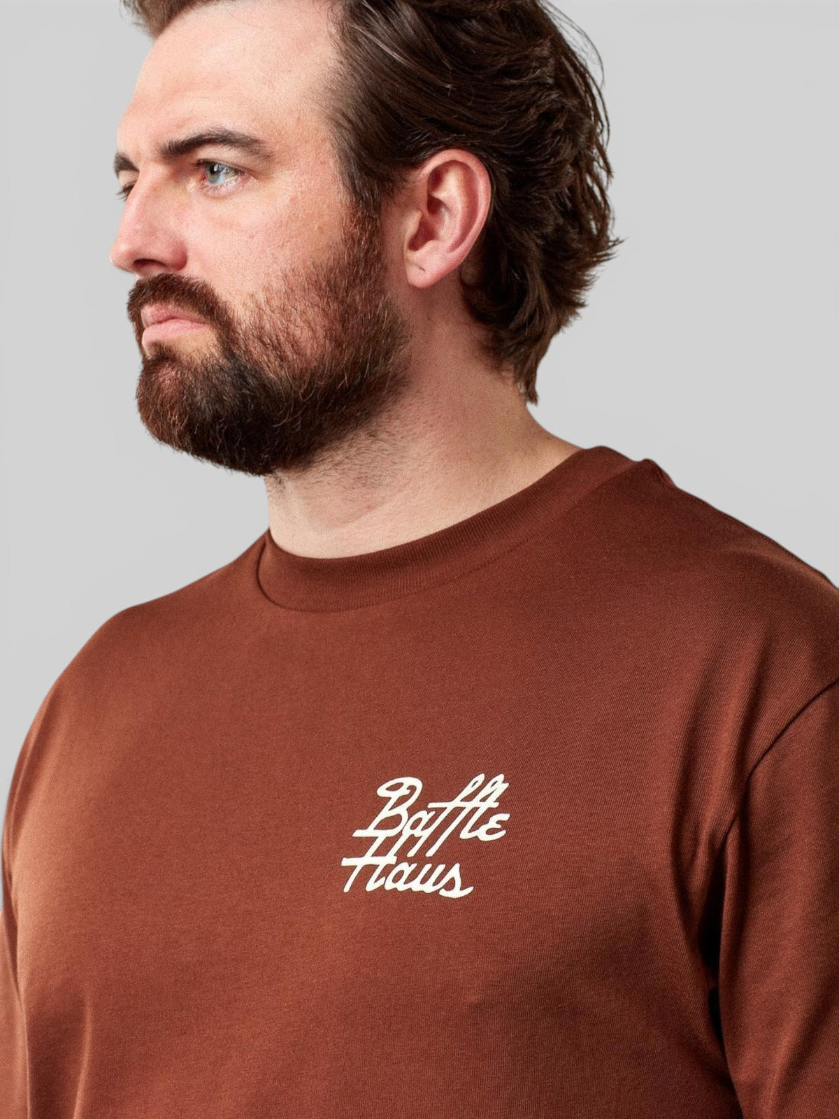 Baffle Haus Mustang Tee in cocoa brown 100% cotton with white script logo on chest worn by a bearded man