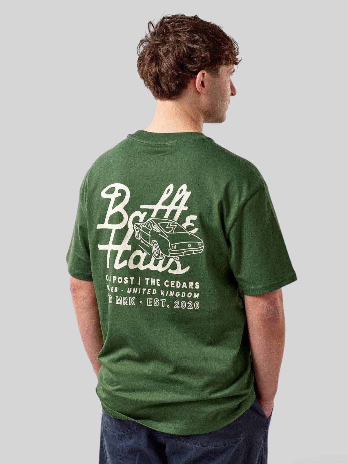 Baffle Haus forest green cotton t-shirt with white mustang car graphic on the back, worn by a male model.