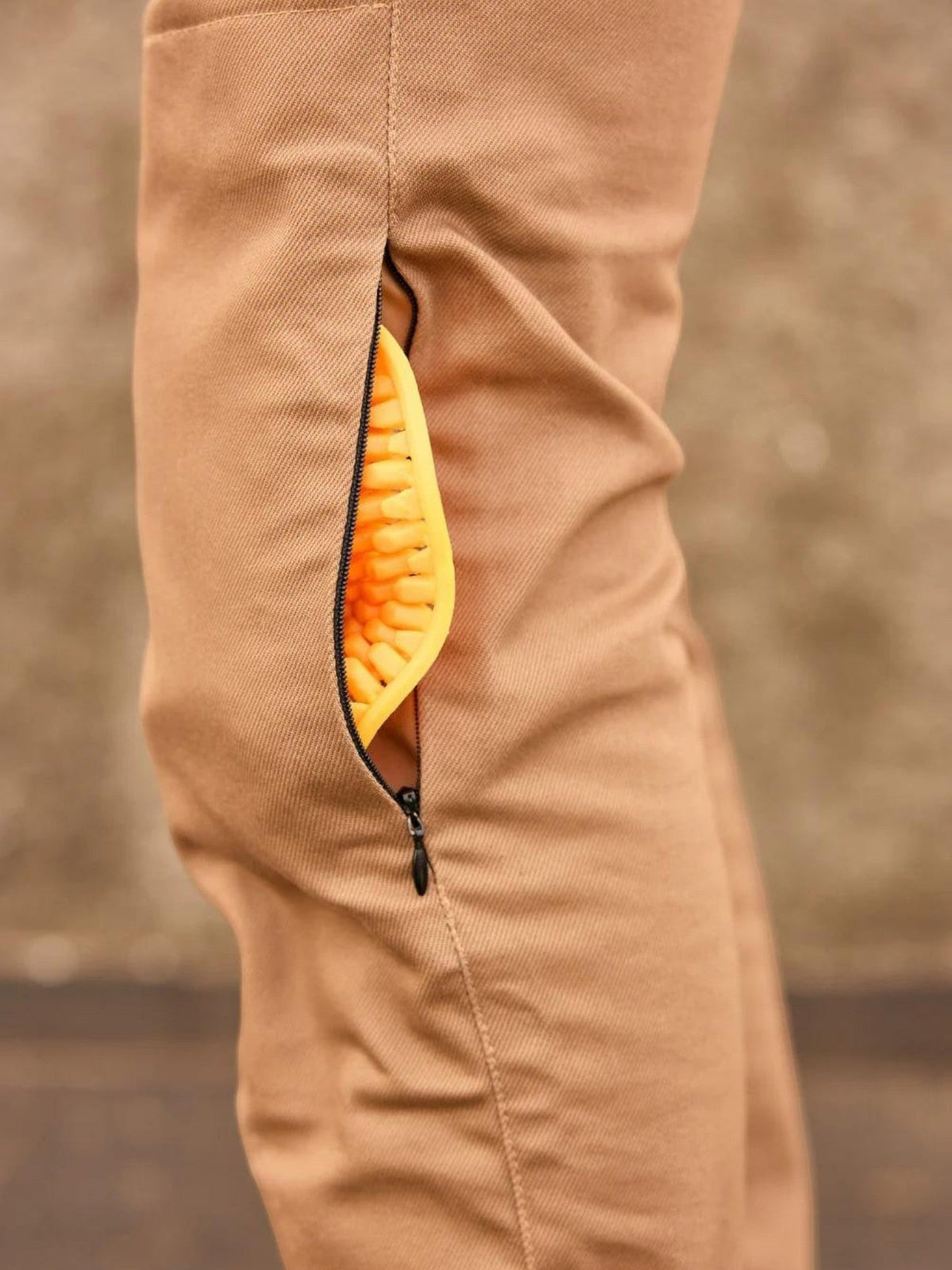 Baffle Haus mustard reinforced cotton cargo trousers with a zippered side pocket revealing a yellow knee protector