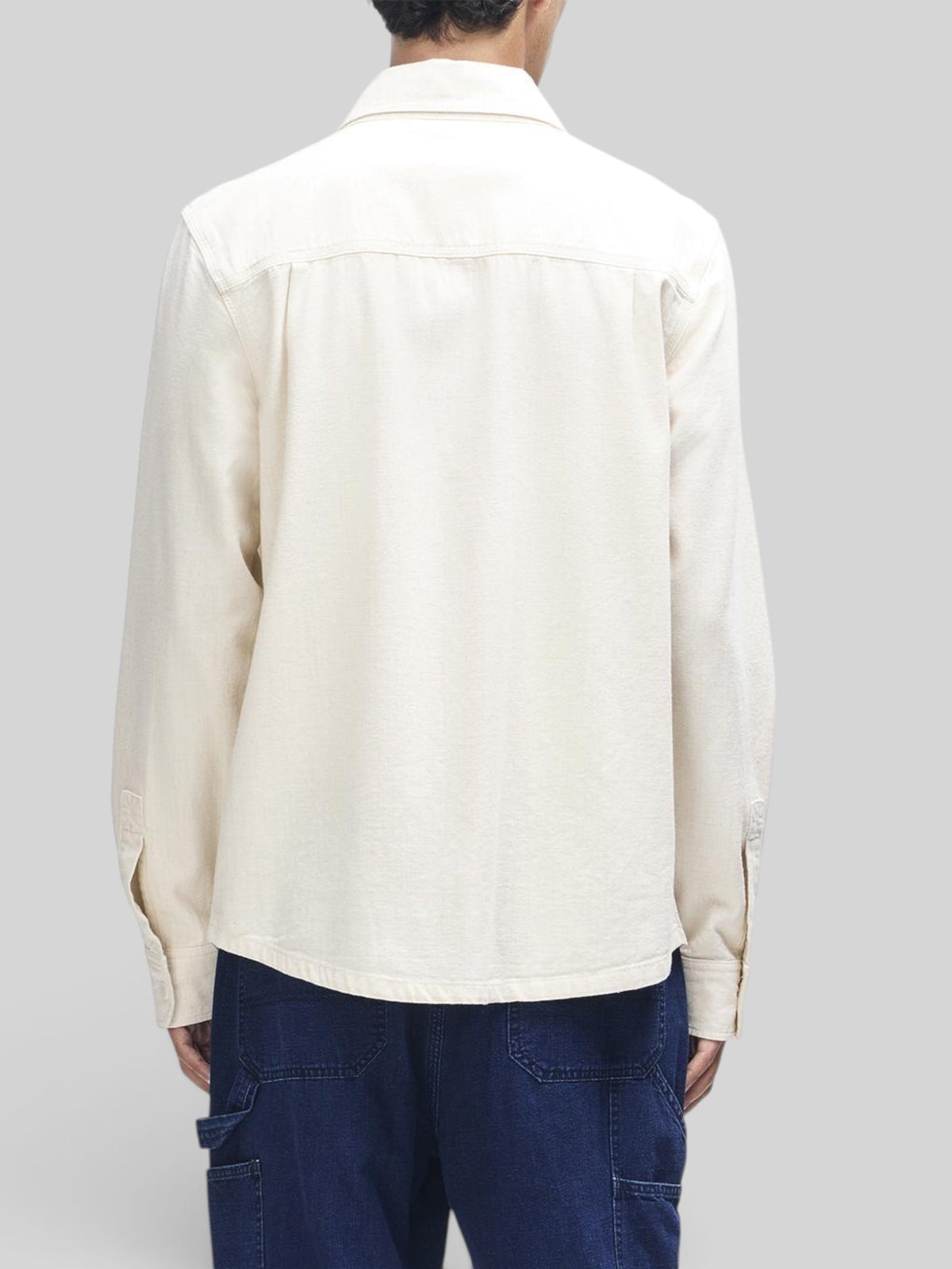 Back view of a man wearing a Baffle Haus natural cotton chambray long sleeve over shirt with a relaxed fit.