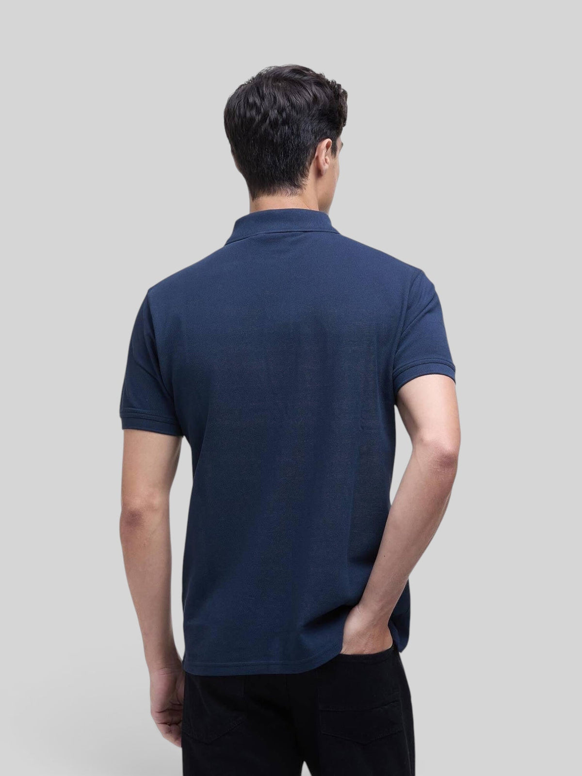 Baffle Haus navy blue cotton pique polo shirt worn by a man, back view showing rib-knit collar and cuff details.