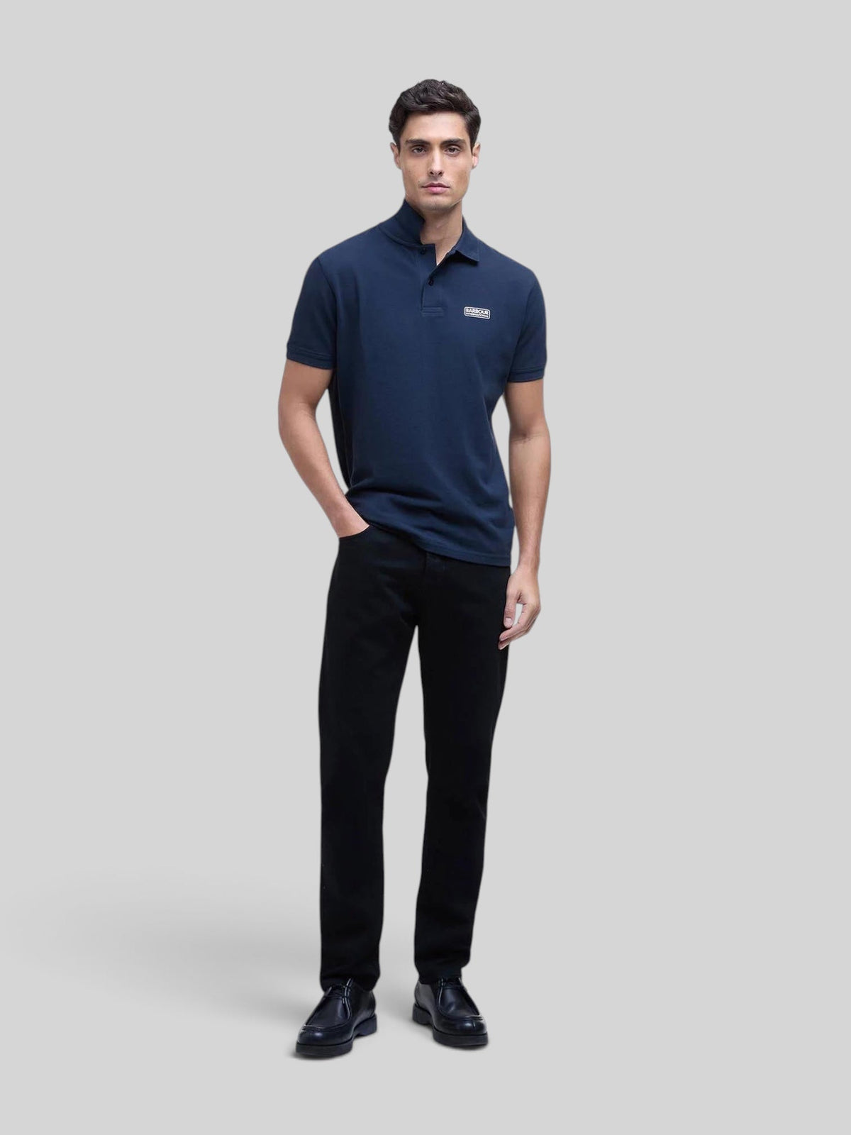 Baffle Haus model wearing a navy blue Barbour International cotton pique polo shirt with a silicone chest logo badge.