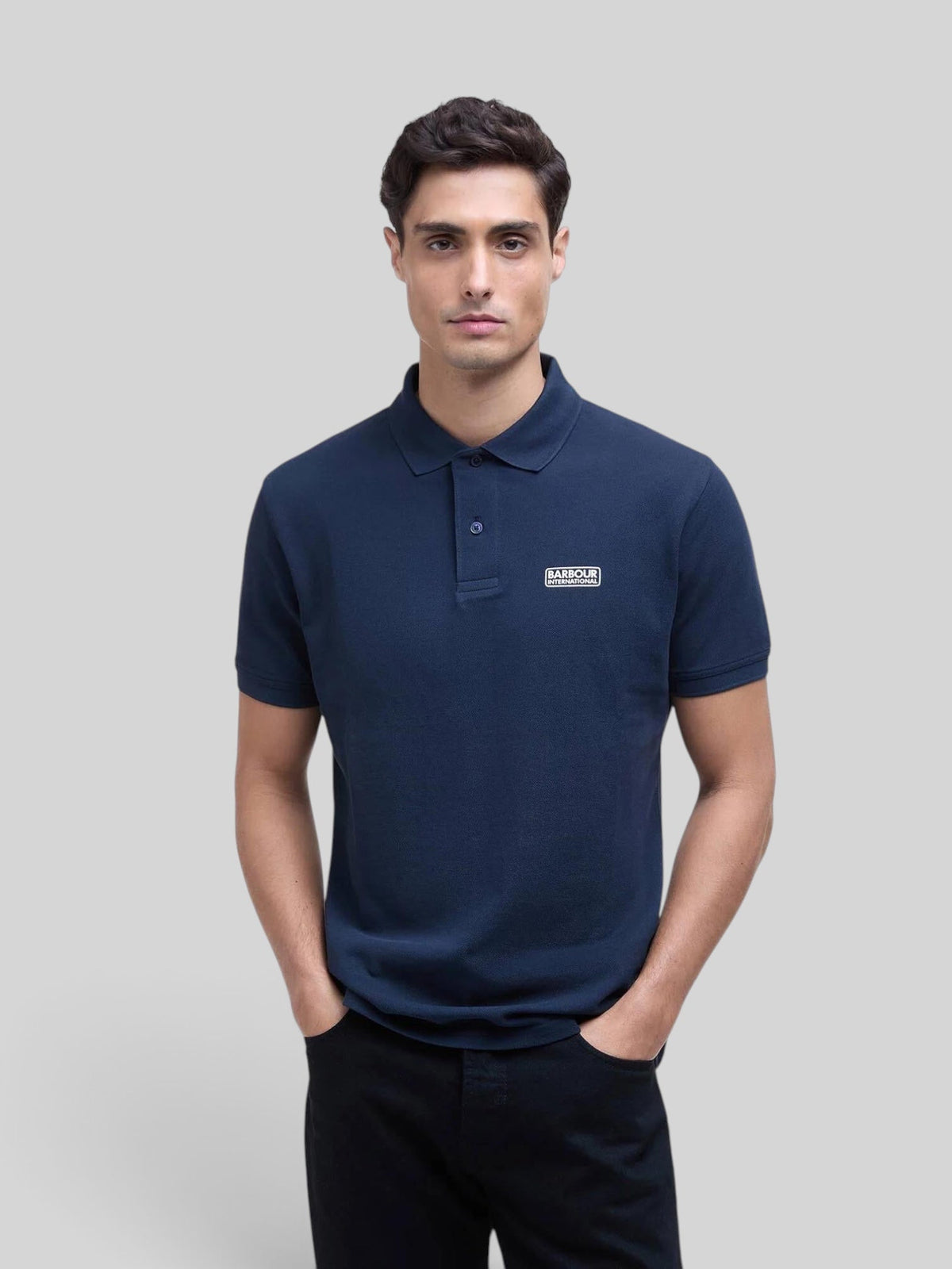 Baffle Haus model wearing a navy blue Barbour International cotton pique polo shirt with rib-knit collar and cuffs.