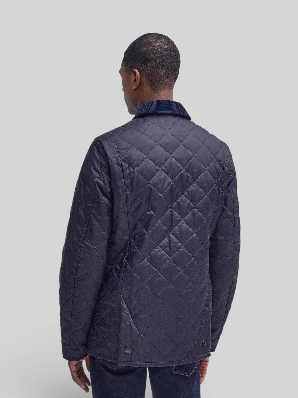 Back view of a man wearing a Baffle Haus Heritage Liddesdale navy diamond-quilted jacket with a corduroy collar.