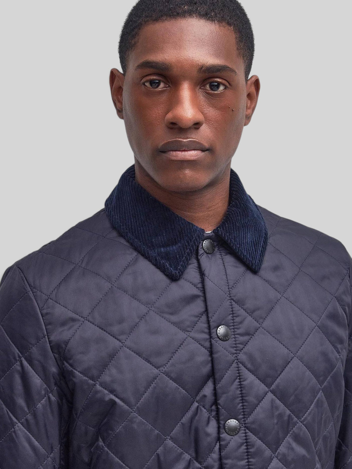 Baffle Haus Heritage Liddesdale navy quilted jacket with a corduroy collar and snap-button front on a male model