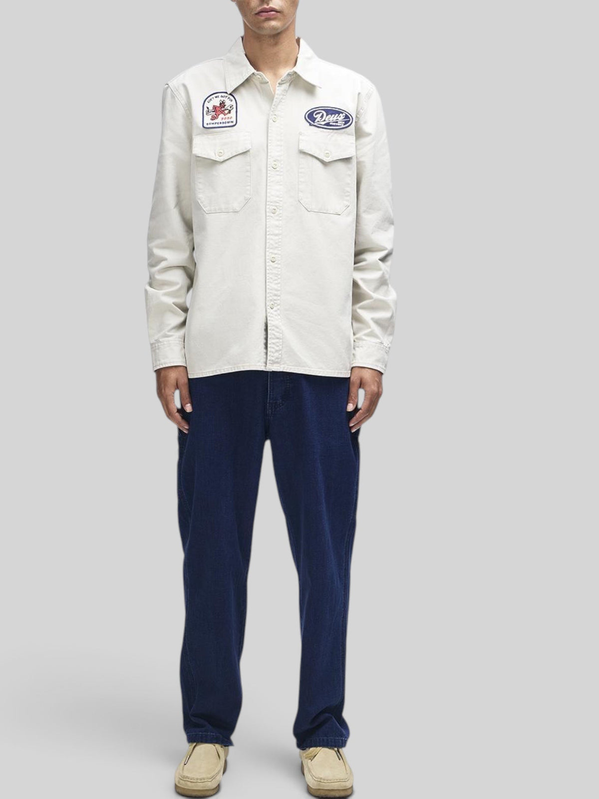 Baffle Haus Nomad shirt in dirty white cotton twill with chest pockets, embroidered patches, and button closure.