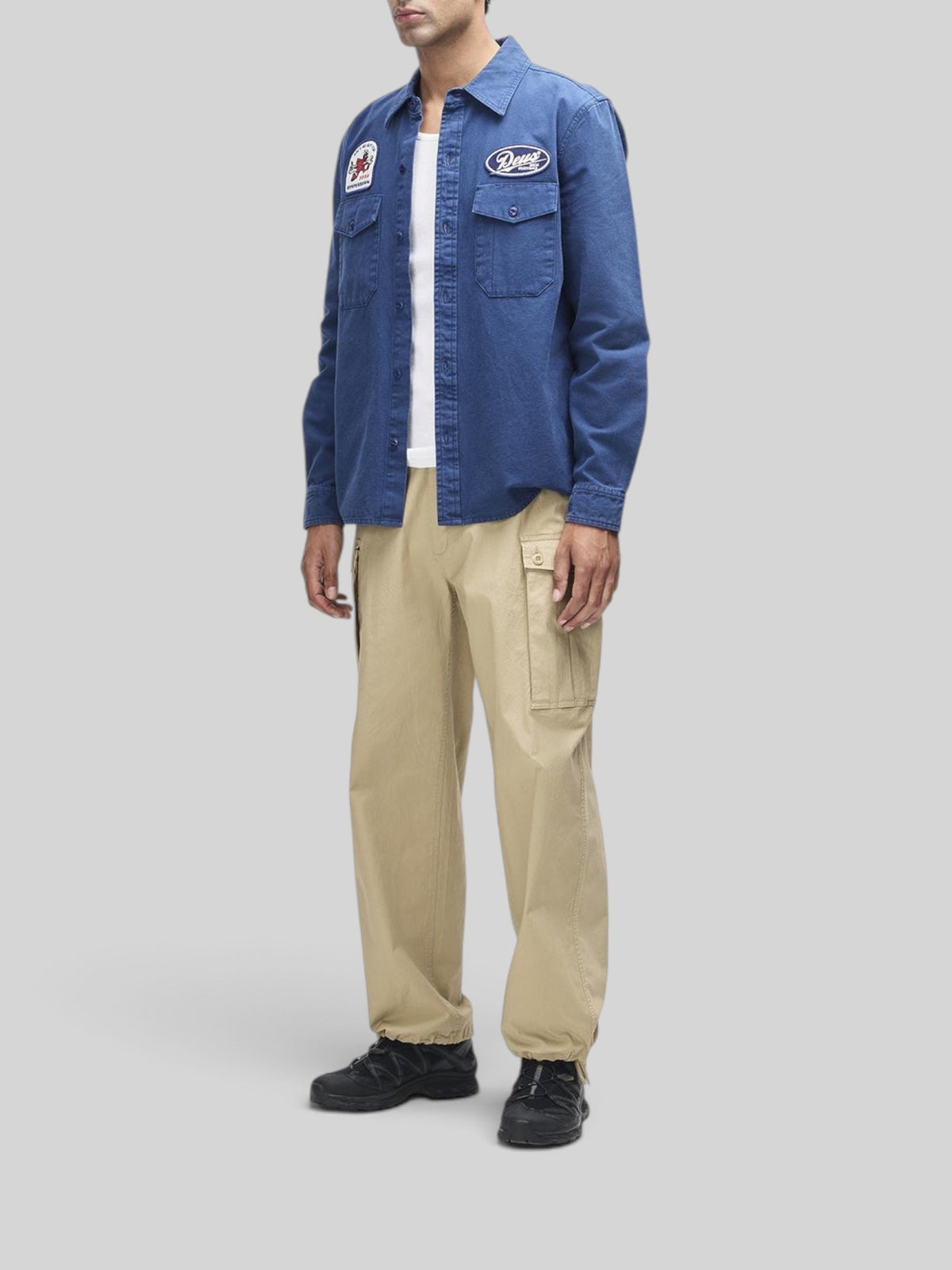 Baffle Haus Nomad mechanic blue cotton twill overshirt with embroidered patches and chest pockets on a male model.