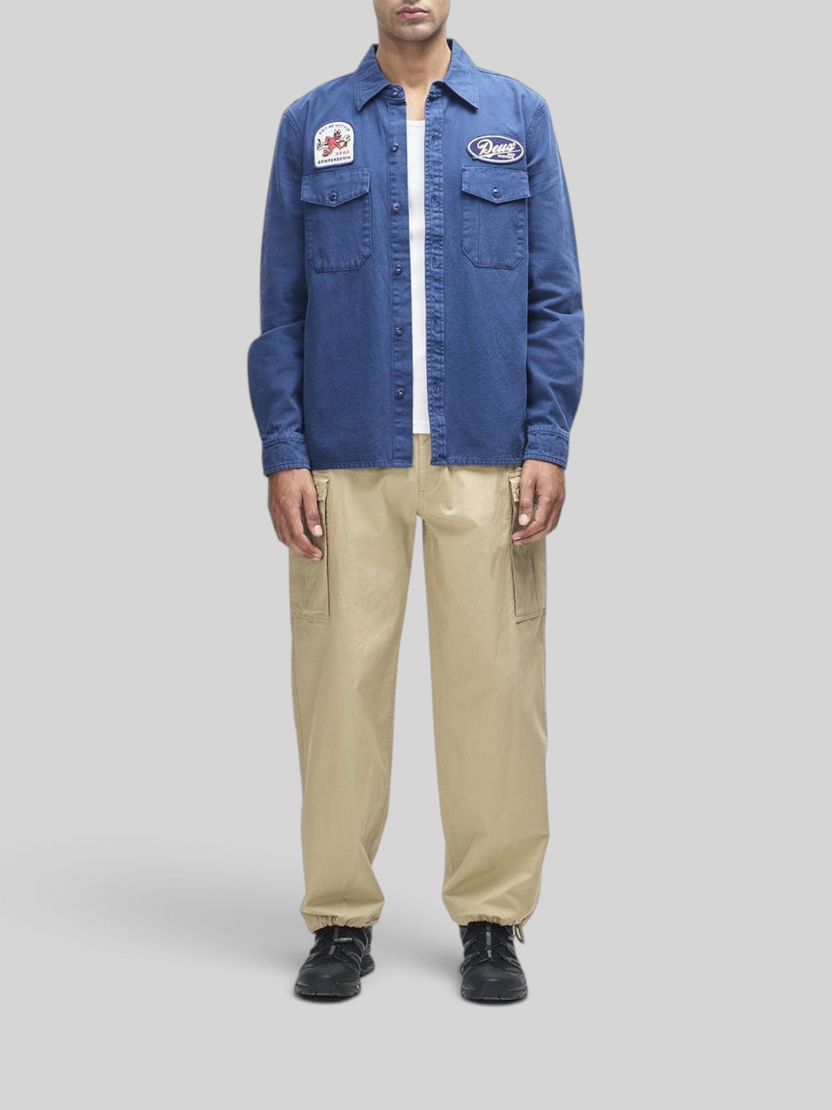 Baffle Haus Nomad shirt in mechanic blue cotton twill with embroidered patches and chest pockets on a male model