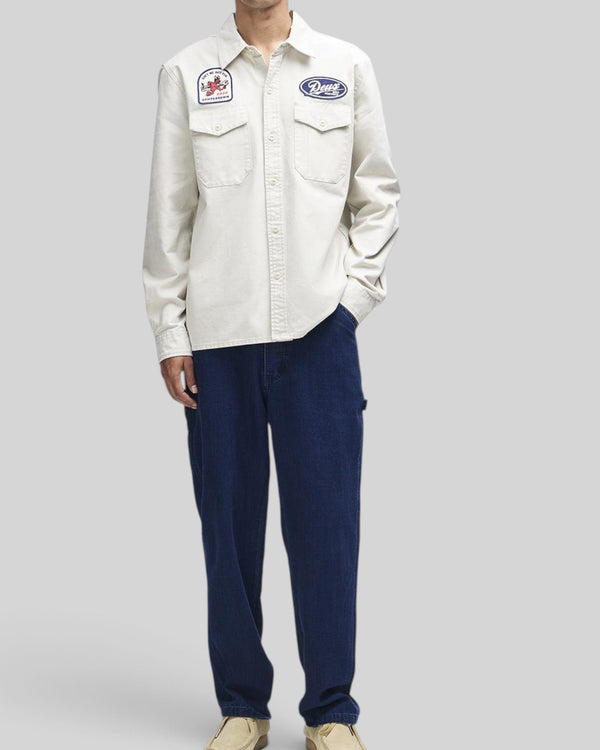 Baffle Haus Nomad shirt in dirty white cotton twill with embroidered patches, chest pockets, and button closure.