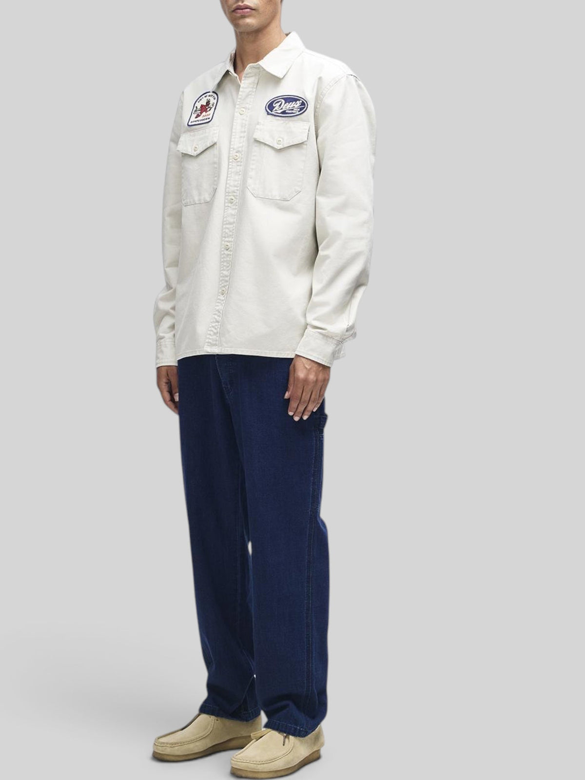 Baffle Haus Nomad shirt in dirty white cotton twill with embroidered patches, chest pockets, and button closure.