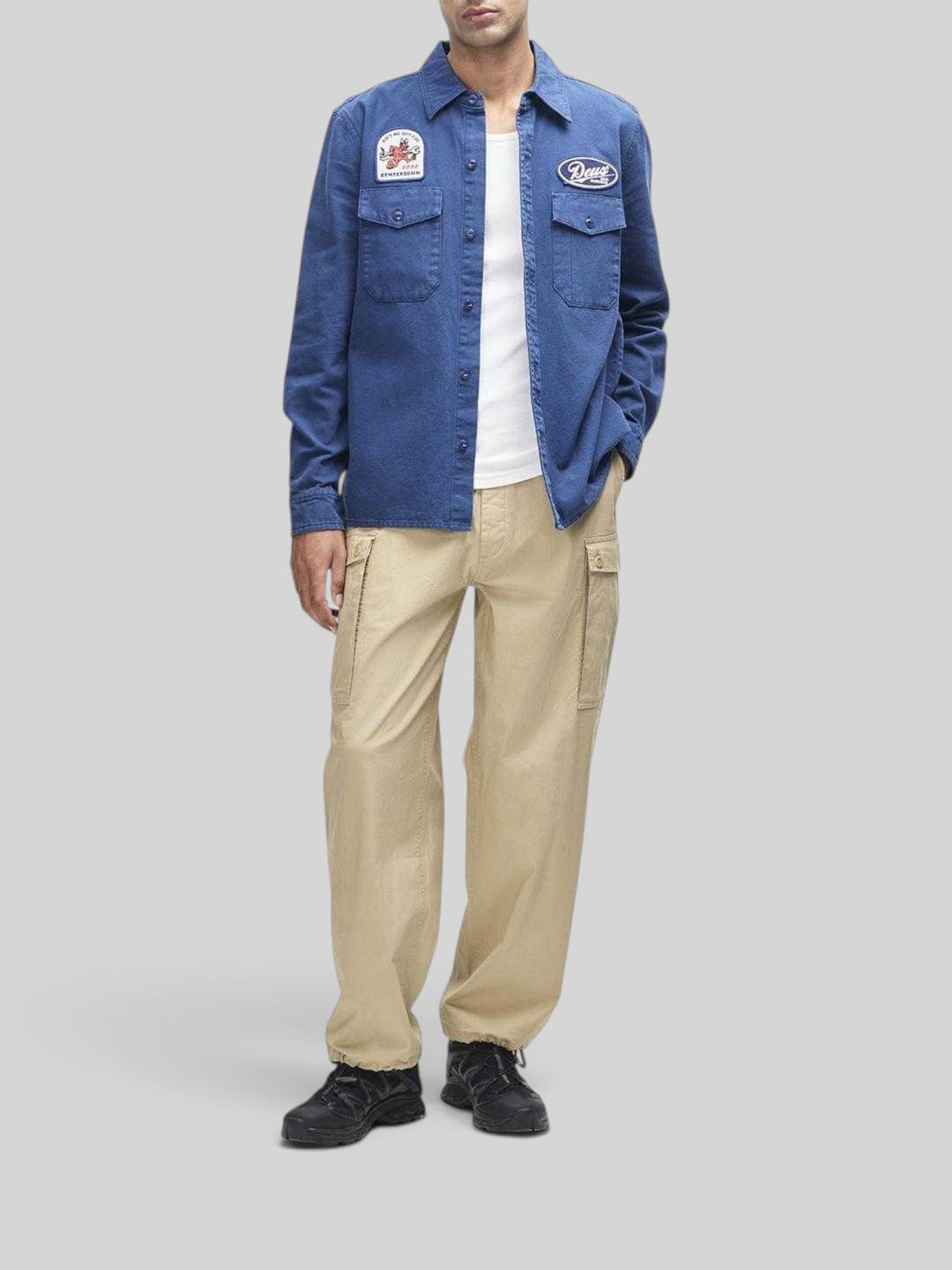 Baffle Haus Nomad Shirt in mechanic blue cotton twill with embroidered patches, chest pockets, and button closure.