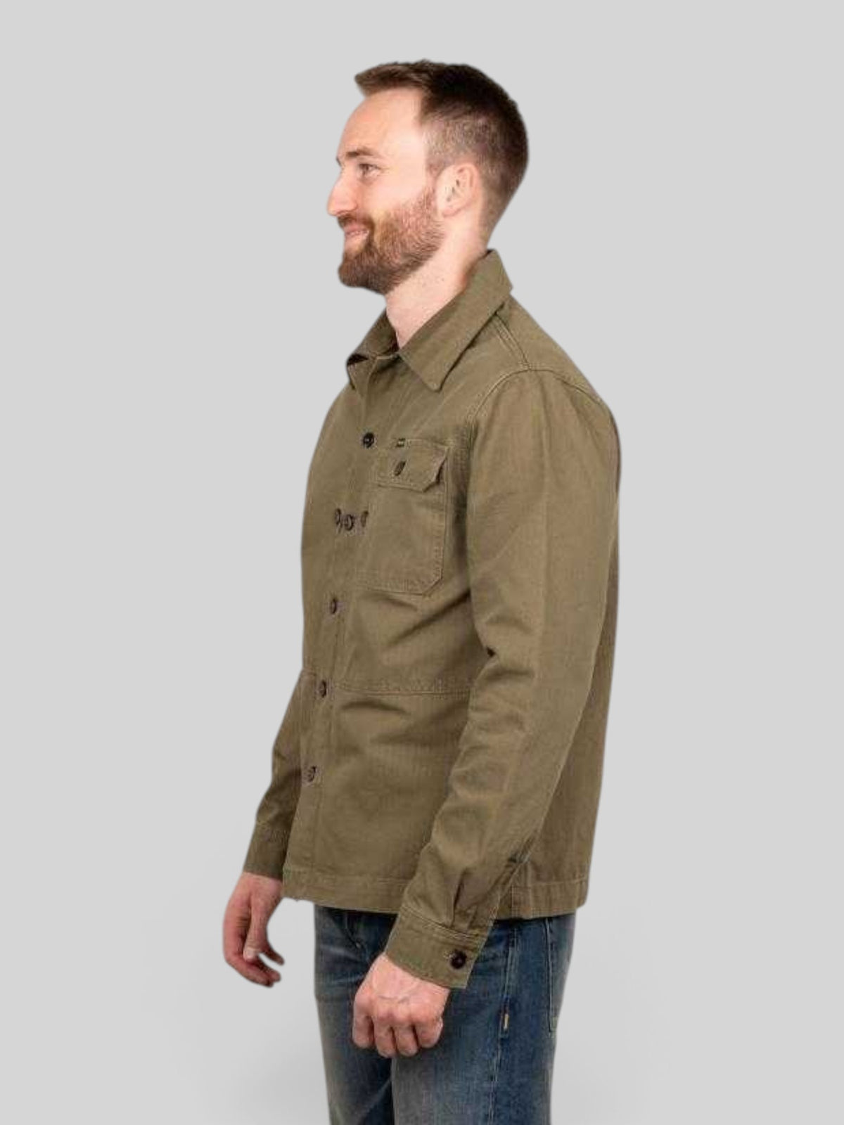 Baffle Haus 1967 Utility Shirt in olive herringbone twill cotton with chest pockets, worn by a man in profile view.