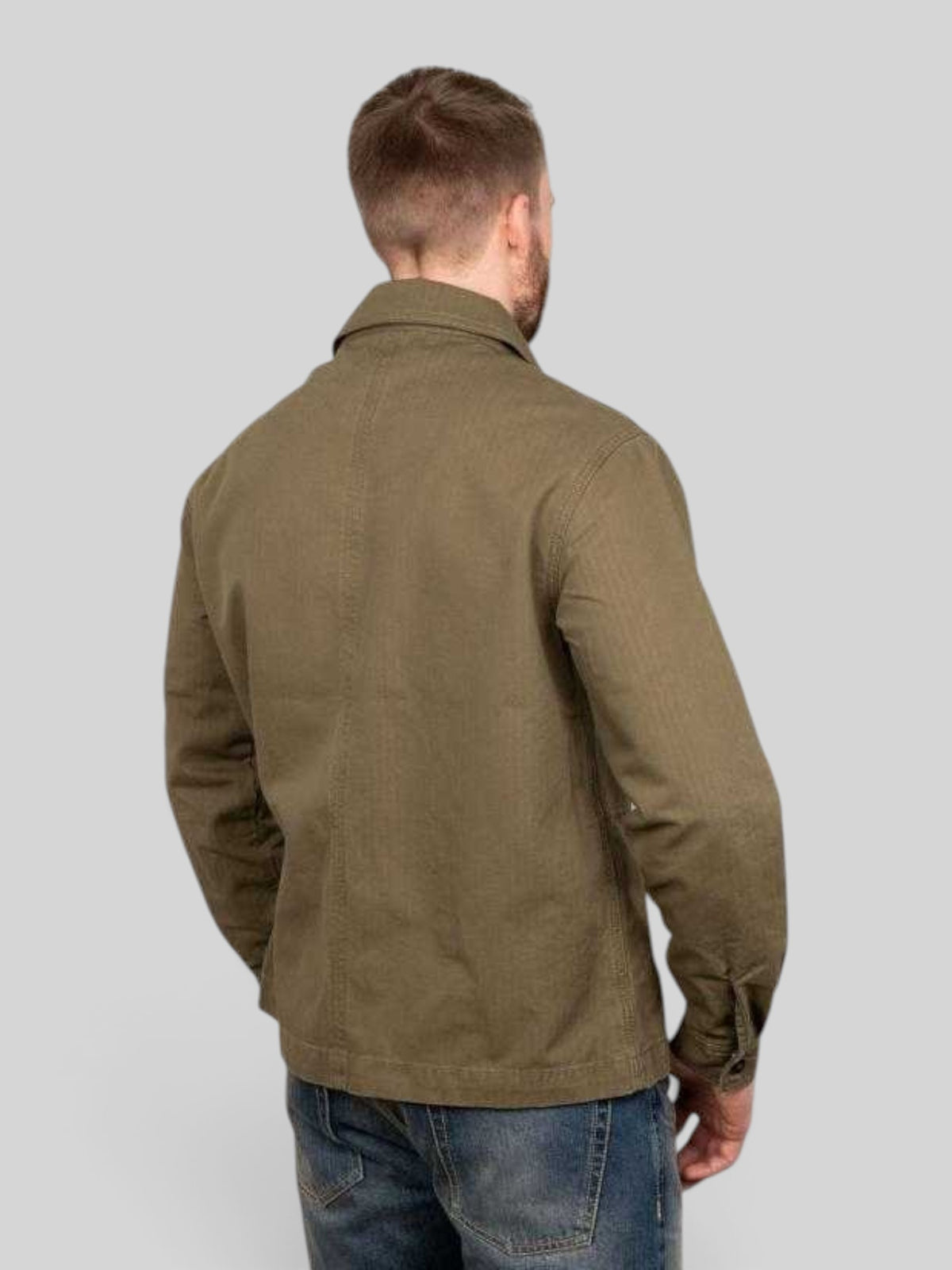 Back view of a man wearing a Baffle Haus 1967 Utility Shirt in olive herringbone twill cotton with a regular fit.