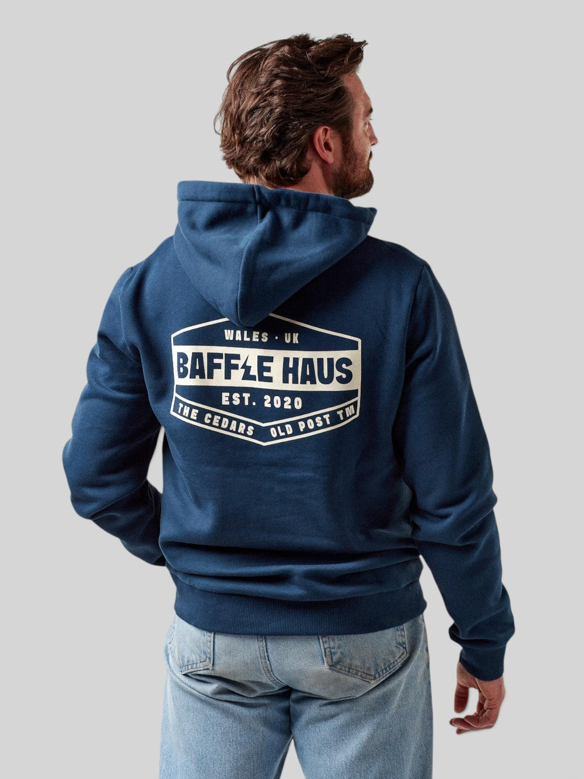 Back view of a man wearing a Baffle Haus pageant blue heavyweight cotton blend hoodie with a white logo graphic.