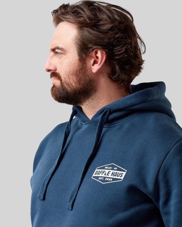 Baffle Haus retro hoodie in pageant blue with a white chest logo, worn by a man in a side profile view.