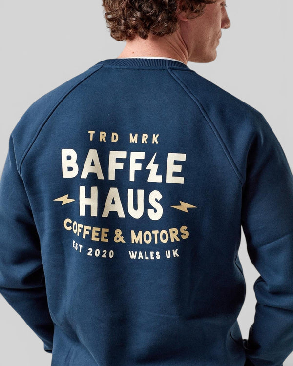 Baffle Haus Coffee & Motors sweatshirt in pageant blue with cream graphic print on the back, worn by a male model.