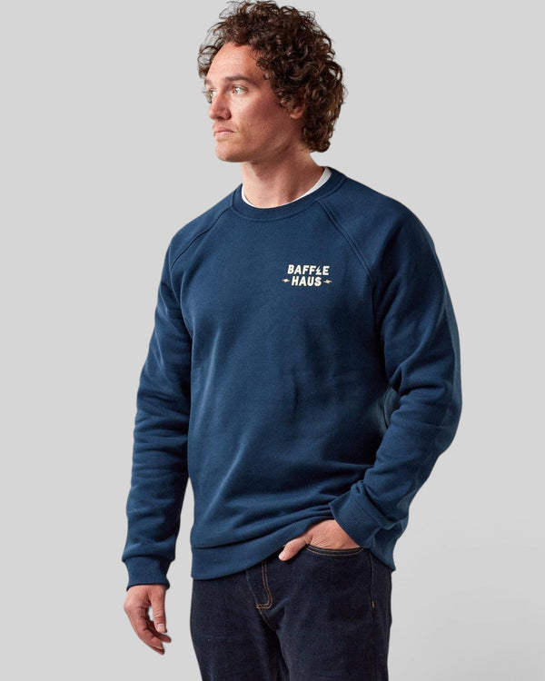 Model wearing a Baffle Haus Coffee & Motors sweatshirt in pageant blue with a white chest logo on a grey background