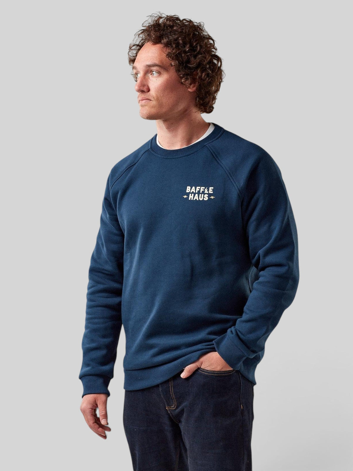 Model wearing a Baffle Haus Coffee & Motors sweatshirt in pageant blue with a white chest logo on a grey background
