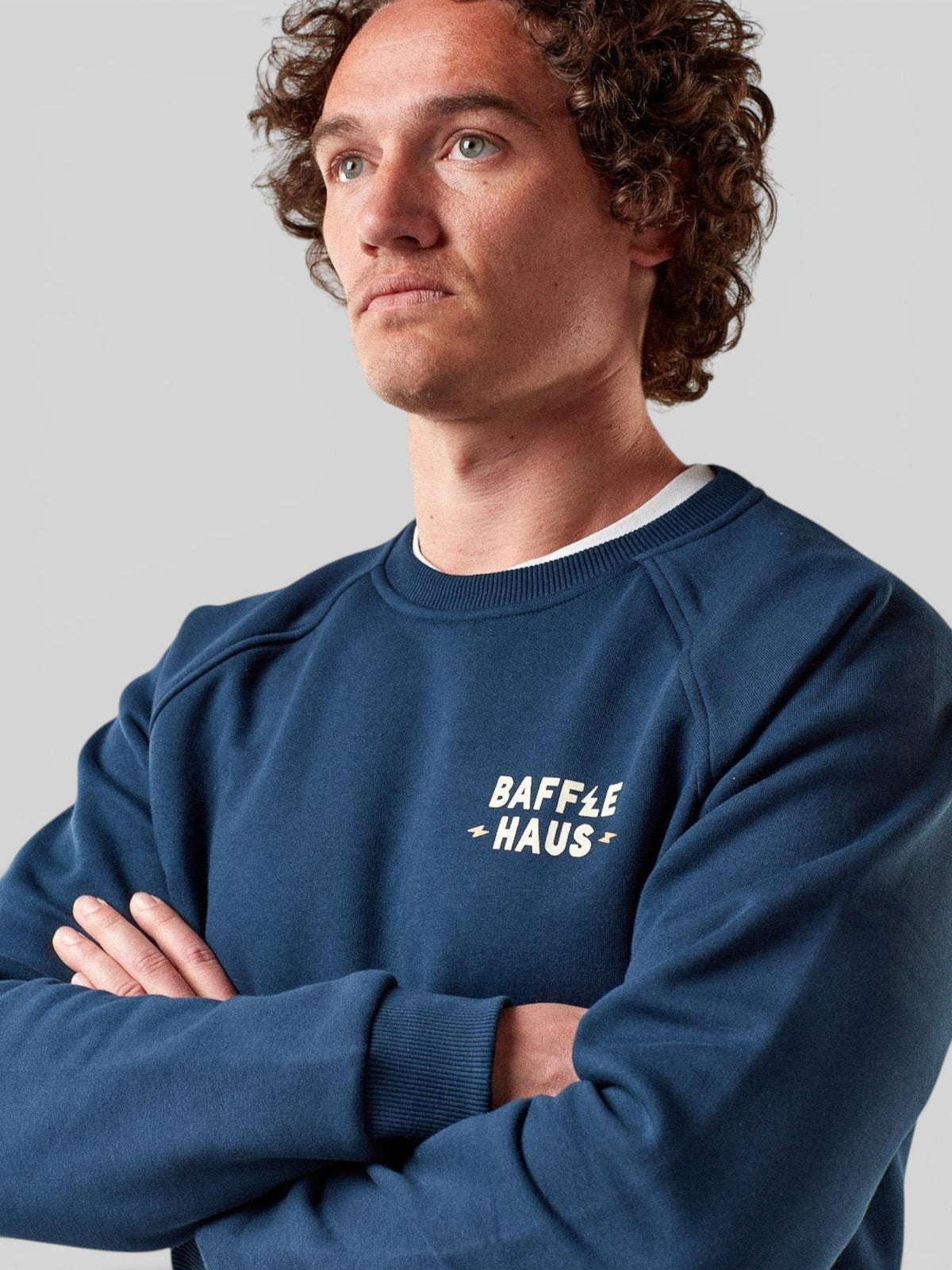 Baffle Haus Coffee & Motors sweatshirt in pageant blue with white chest logo, worn by a model with curly hair.