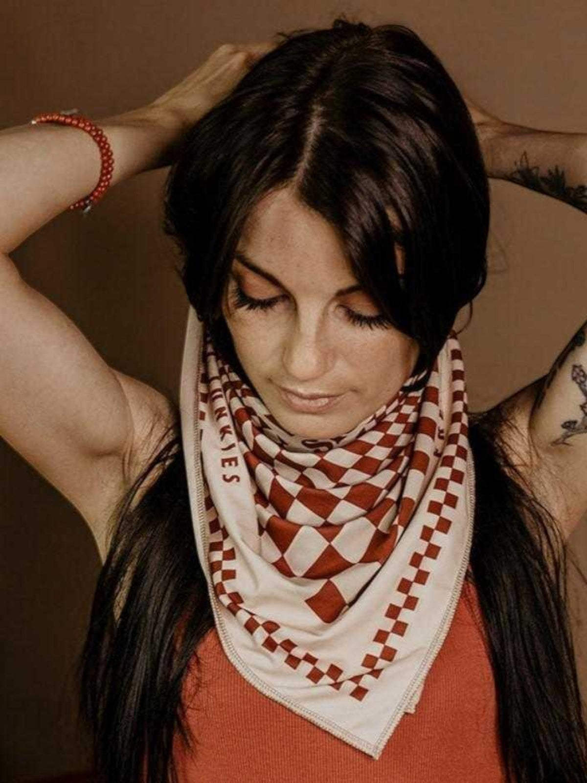 Baffle Haus Petrol Junkies scarf featuring a terracotta and cream psychedelic checkerboard pattern on a woman