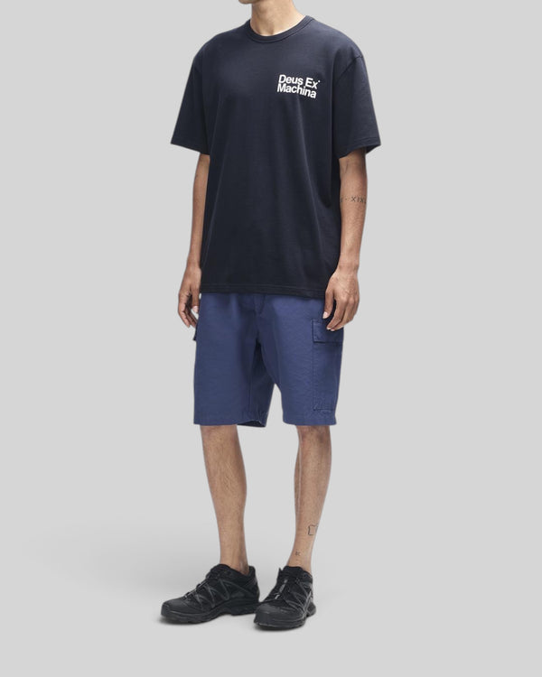 Baffle Haus Plenty Good Tee in black featuring a chest print, worn with blue cargo shorts and black sneakers.