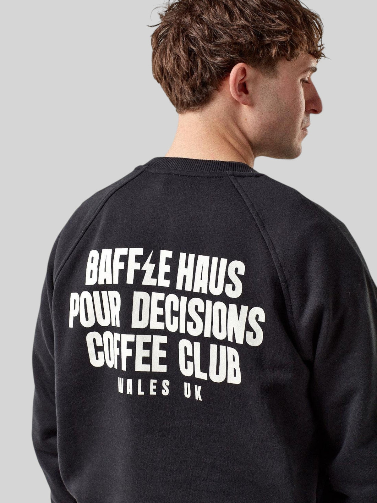 Model wearing a black Baffle Haus Pour Decisions sweatshirt with white back graphic print in French Terry cotton