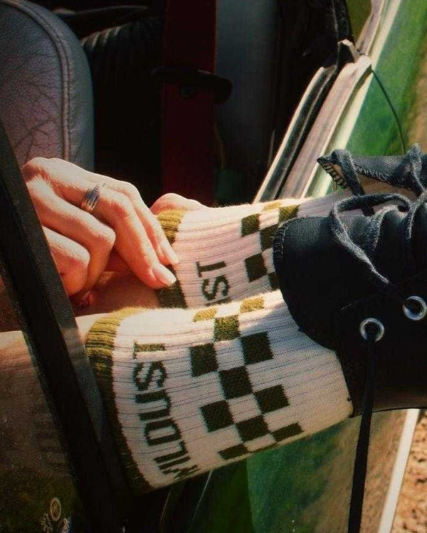 Baffle Haus race green and ecru checkered socks with double-fleece base worn with black boots in a car