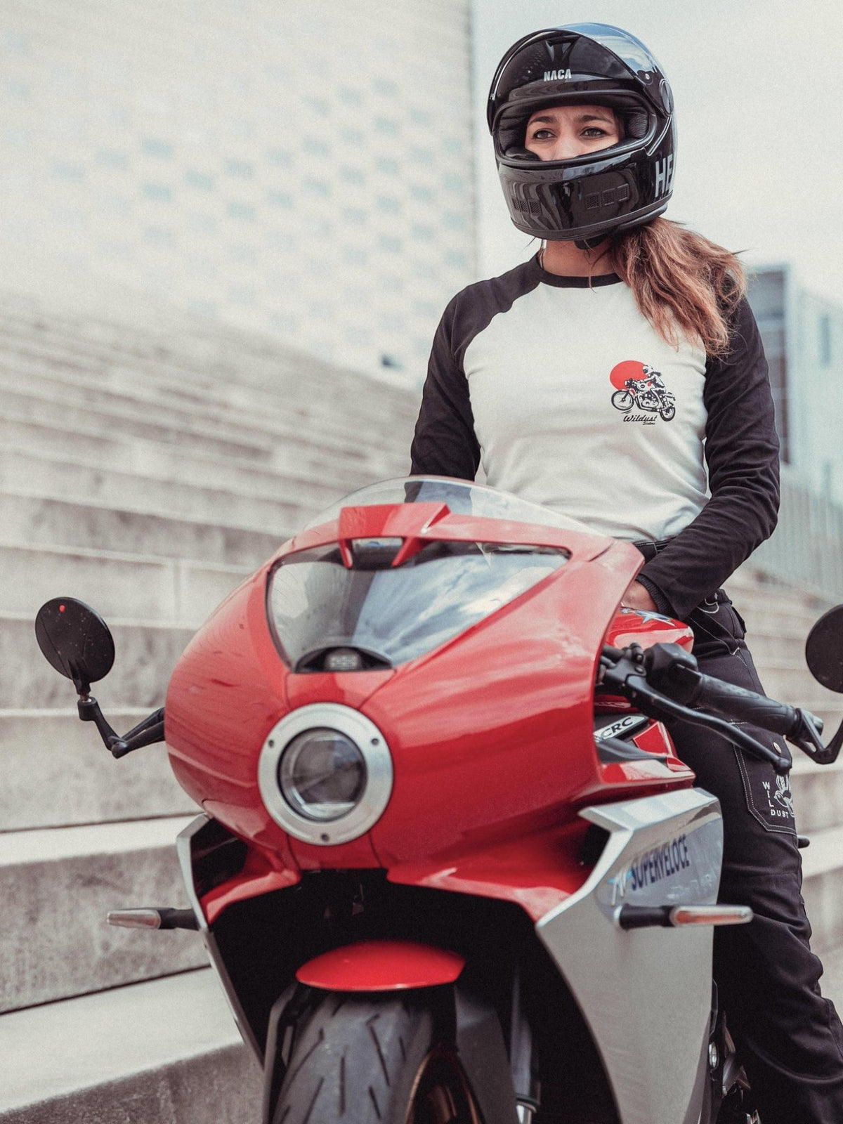 Baffle Haus Rebel long sleeve raglan tee with black sleeves and white body, worn by a woman on a red sport motorcycle.