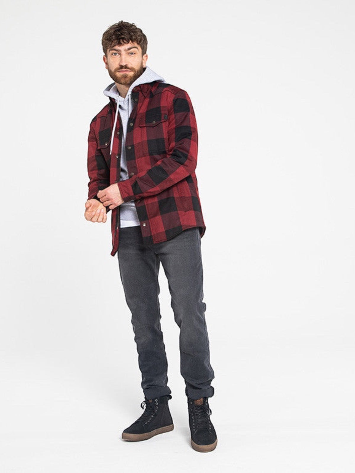 Baffle Haus Motoshirt in red and black plaid worn by a man over a grey hoodie and dark jeans against a white background