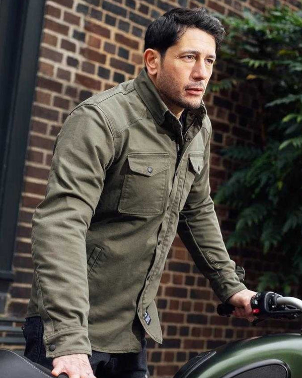 Baffle Haus Renegade green Cordura riding shirt with protective armour worn by a man standing next to a motorcycle