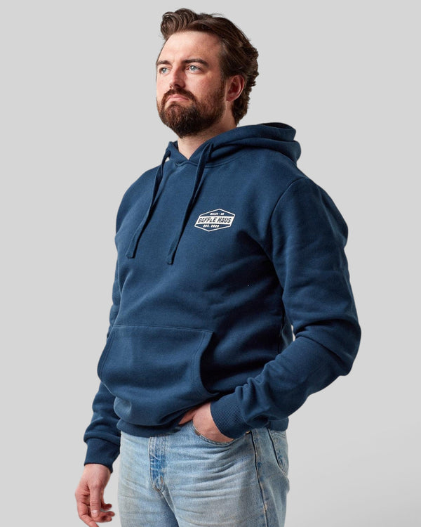 Baffle Haus retro hoodie in pageant blue with a chest logo, worn by a bearded man against a light grey background.