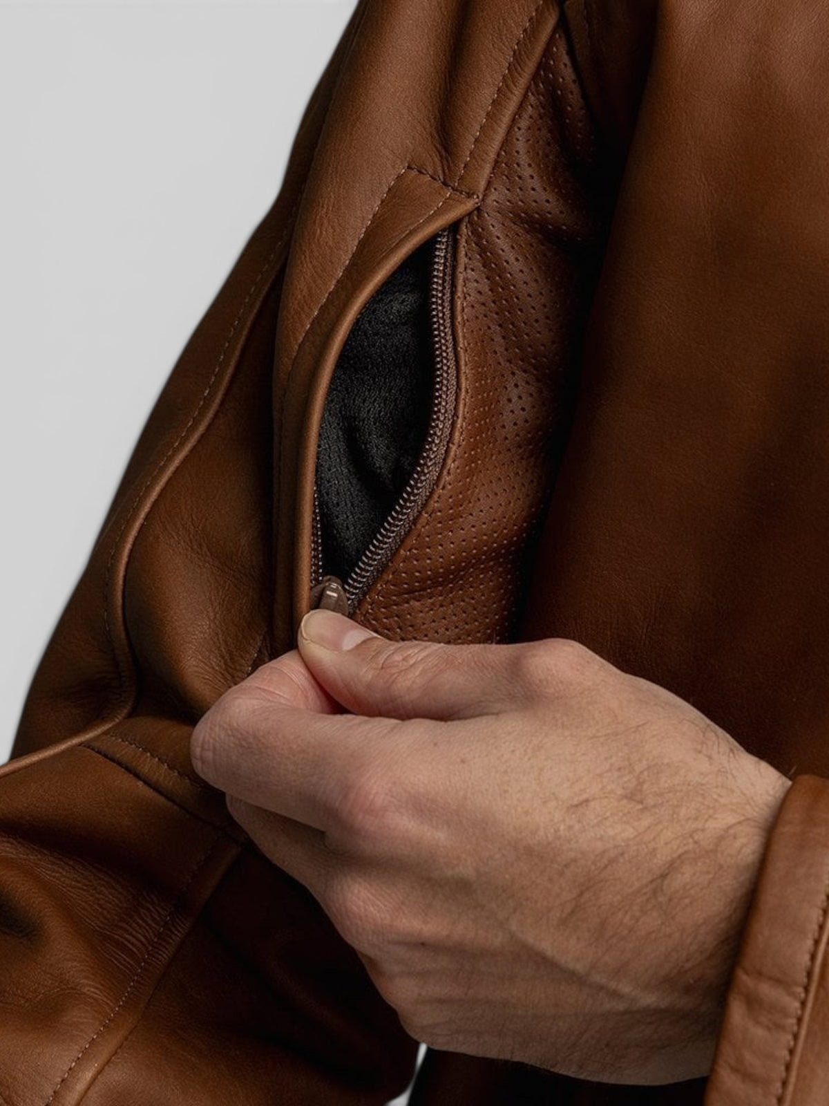 Baffle Haus Motone Revolver tobacco leather jacket showing a close-up of the zippered chest vent and perforated detail