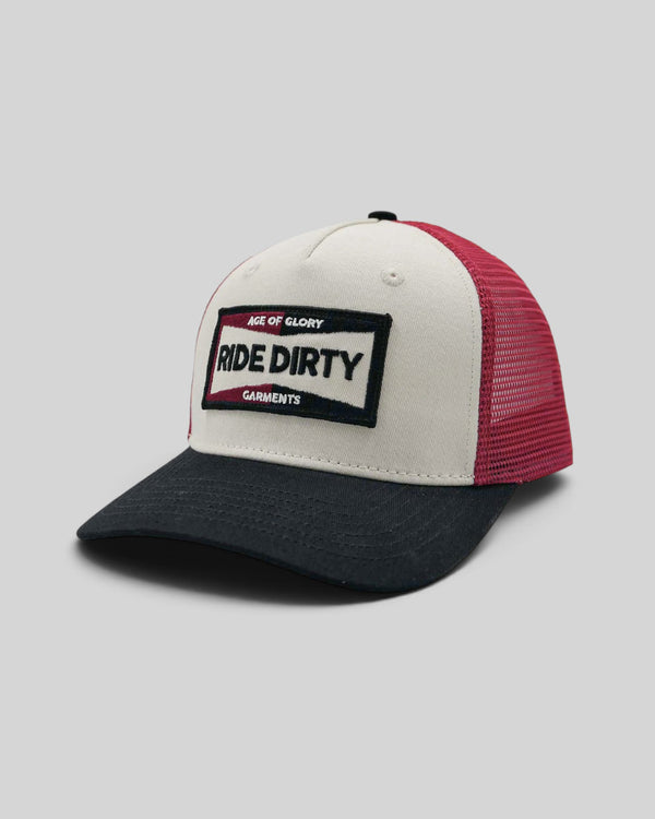 Baffle Haus Ride Dirty trucker cap in white, red, and black with a vintage patch and breathable mesh back.