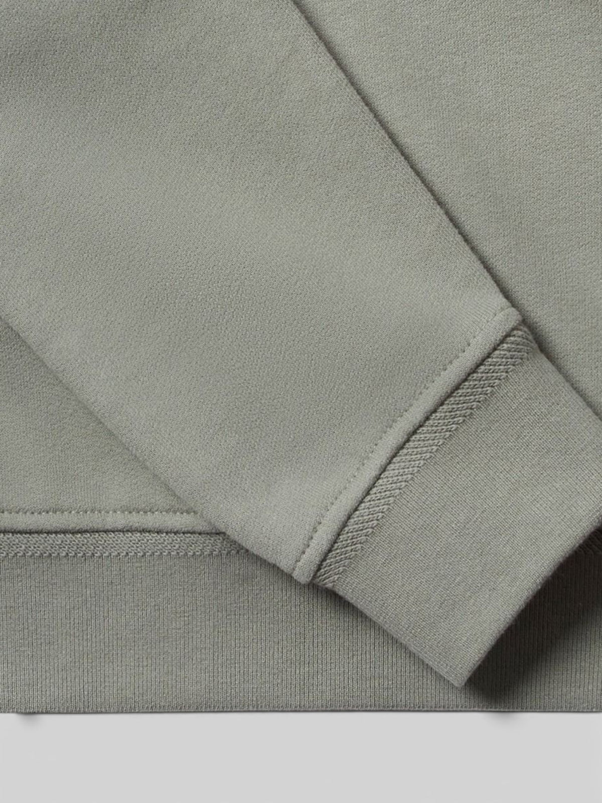 Close-up of the sage green cotton fleece sleeve cuff on a Baffle Haus quarter zip jersey sweatshirt.