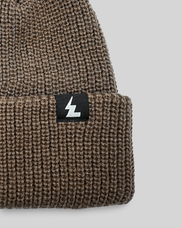 Baffle Haus sand coloured ribbed knit beanie with a woven logo patch on the folded cuff