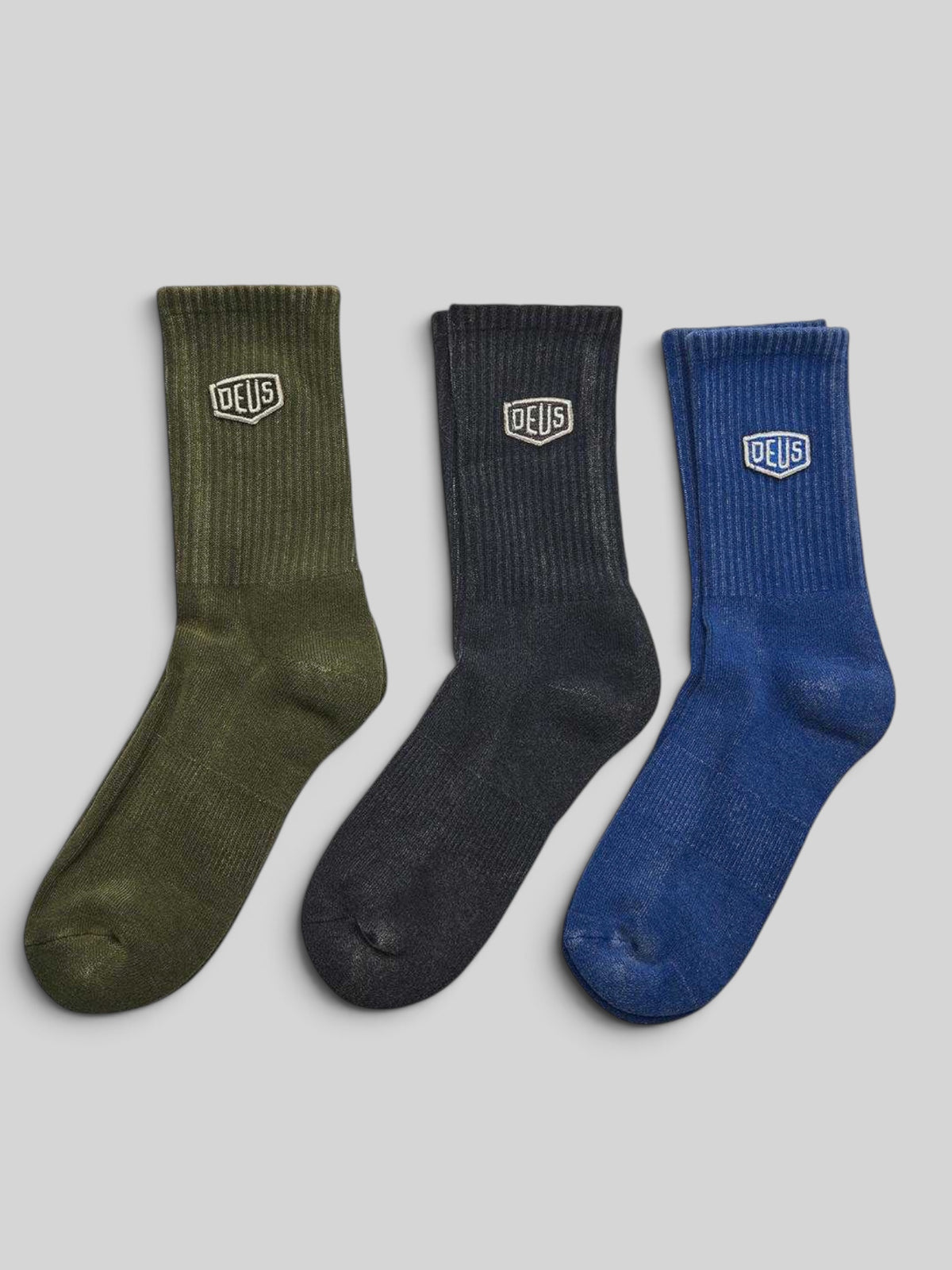 Baffle Haus Shield garment dyed cotton blend socks in olive, black, and blue with tonal Deus shield embroidery.