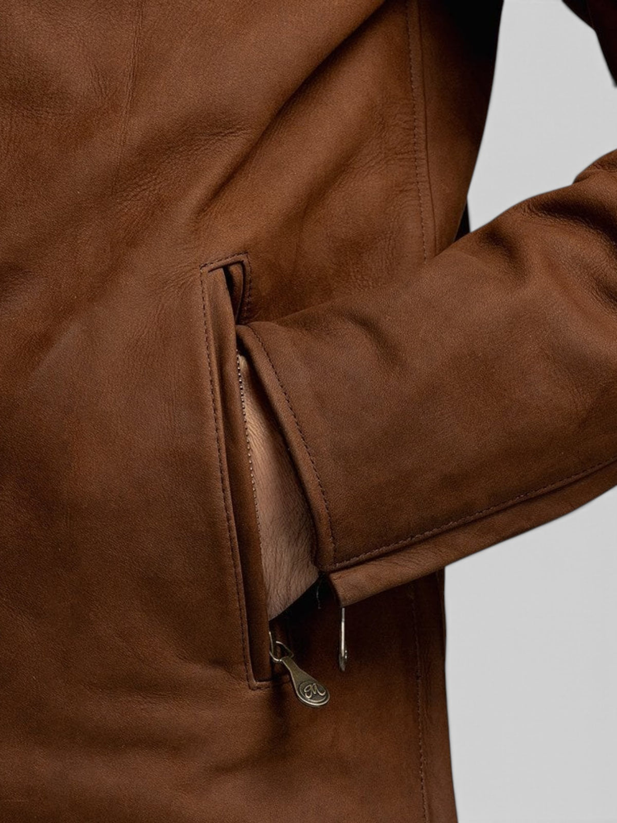 Close-up of the Baffle Haus Shōgun mahogany nubuck leather jacket showing the zippered hand-warmer pocket detail.
