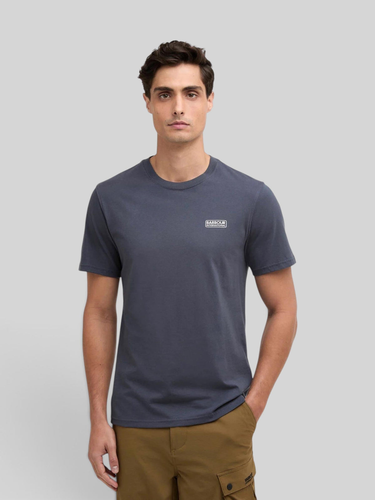 Baffle Haus storm grey cotton crew neck t-shirt with small chest logo worn by a man against a neutral background