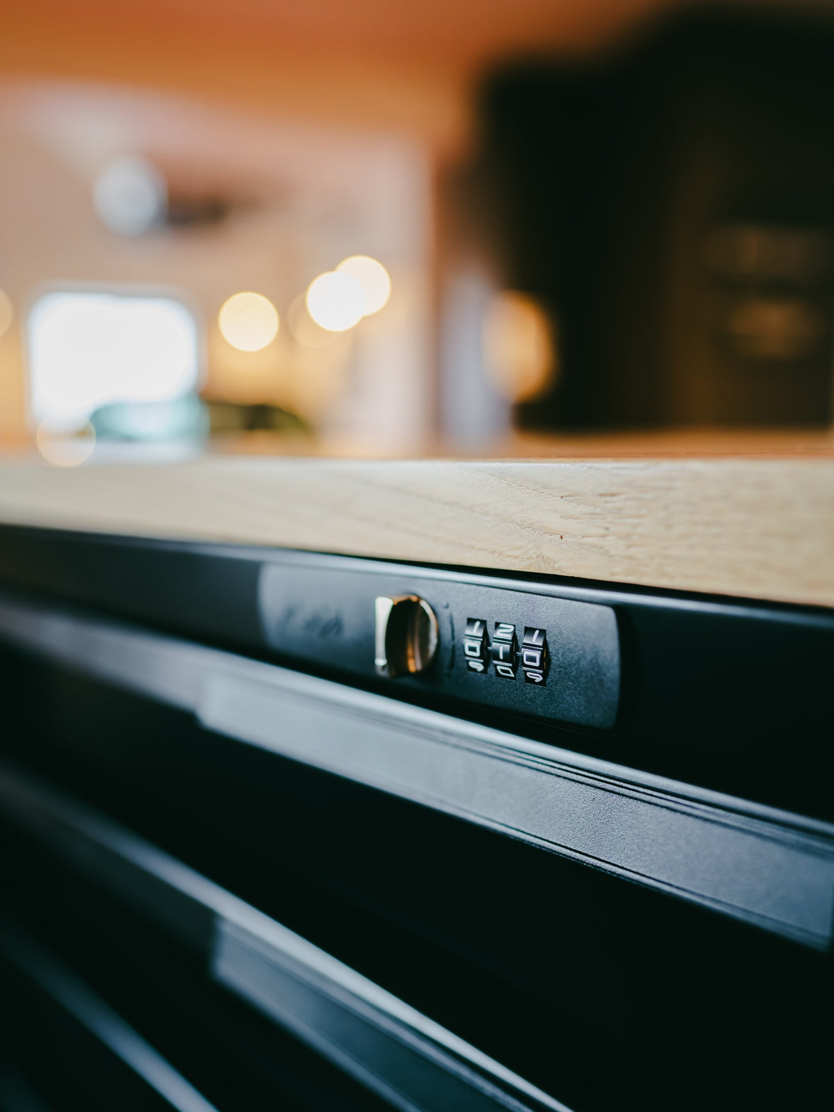 Close-up of a black Baffle Haus tool box featuring a secure combination lock mechanism on a wooden workbench.